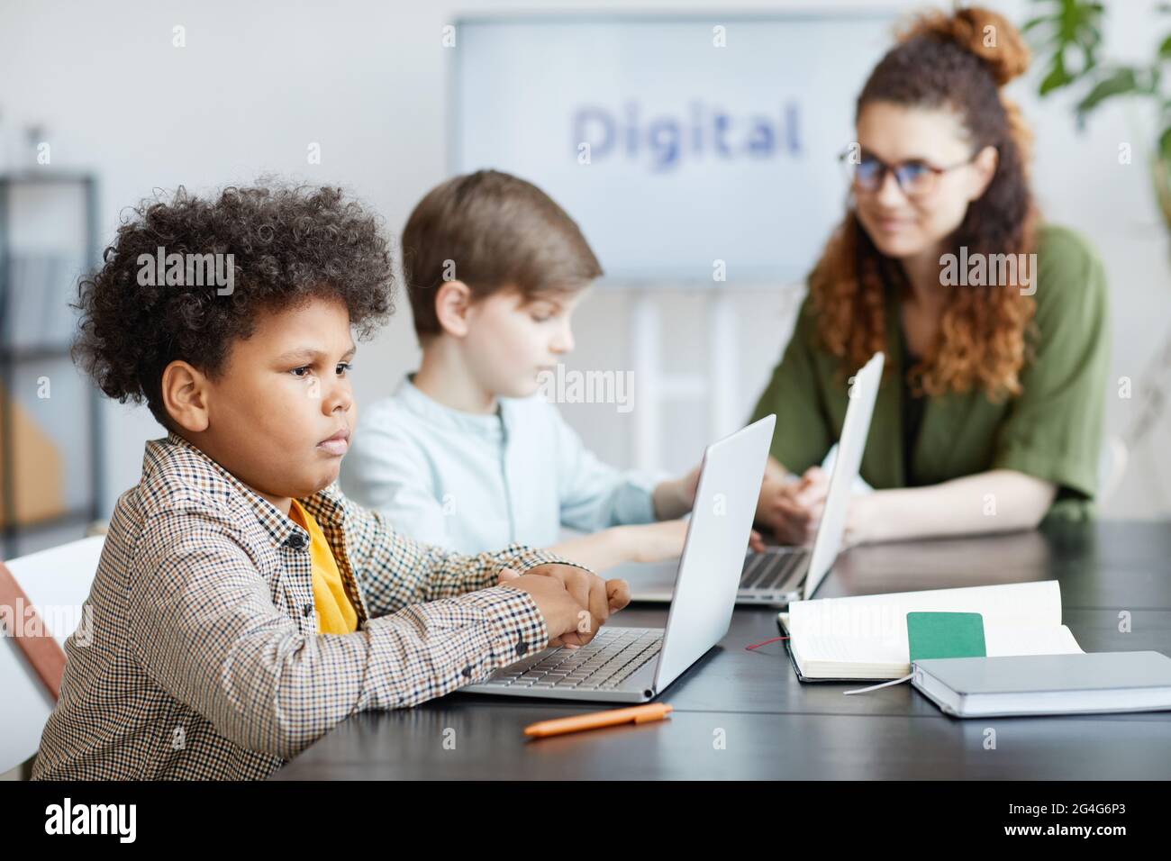Side view portrait of African-American schoolboy using computer in IT ...