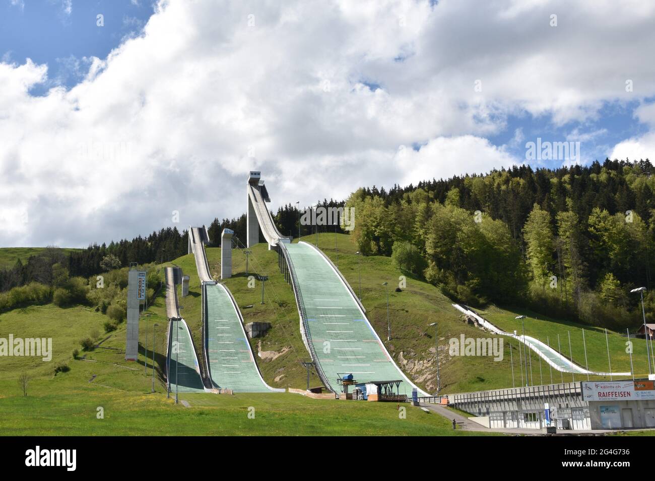 National Ski jumping venue of Switzerland in Eschbach, Einsiedeln surrounded by green forest under blue sky during summer time. Stock Photo