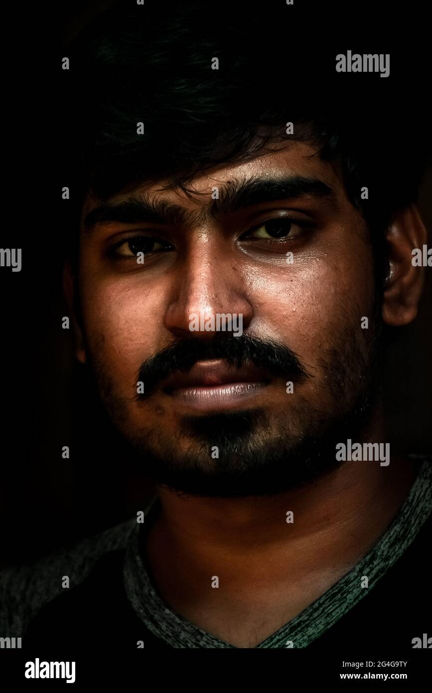 Man in dark.Young beard face of asian Artistic portrait of man with beard  in dark object,face staring at camera,in spotlight. Subtle lighting shadows Stock Photo