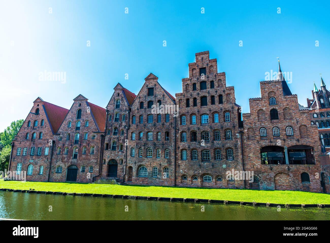 Facade of the medieval salt warehouses or Salzspeicher next to Holsten Gate or Holstentor and the river Trave in Lübeck, Germany Stock Photo