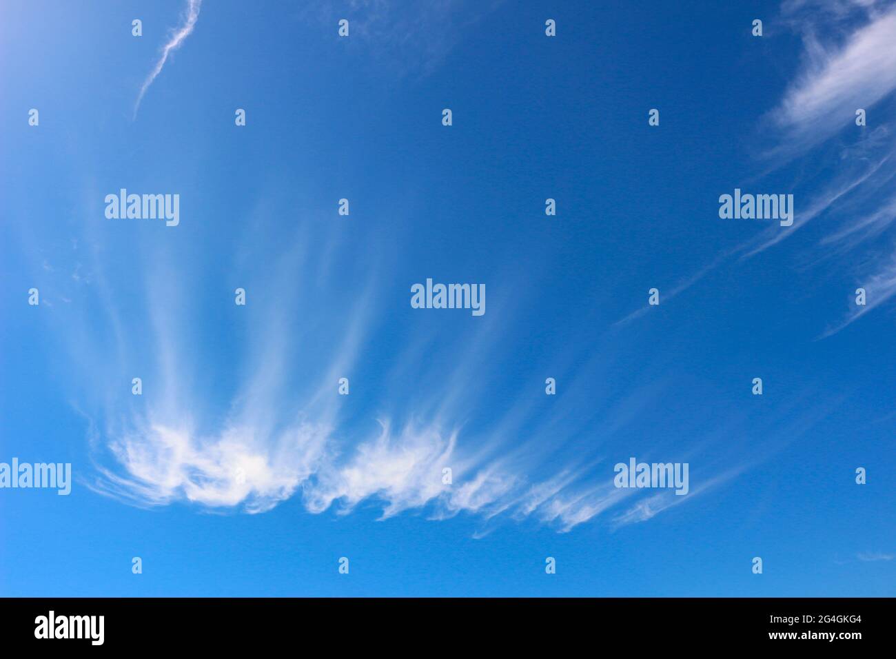 High white cirrus clouds against a deep blue sky Stock Photo