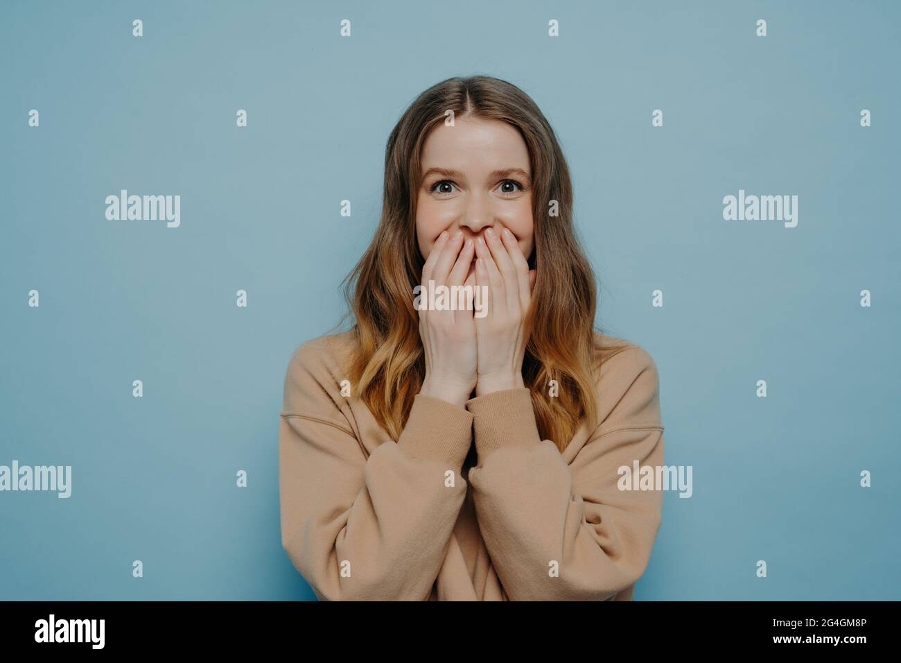 Young surprised teen girl in casual wear on blue background Stock Photo
