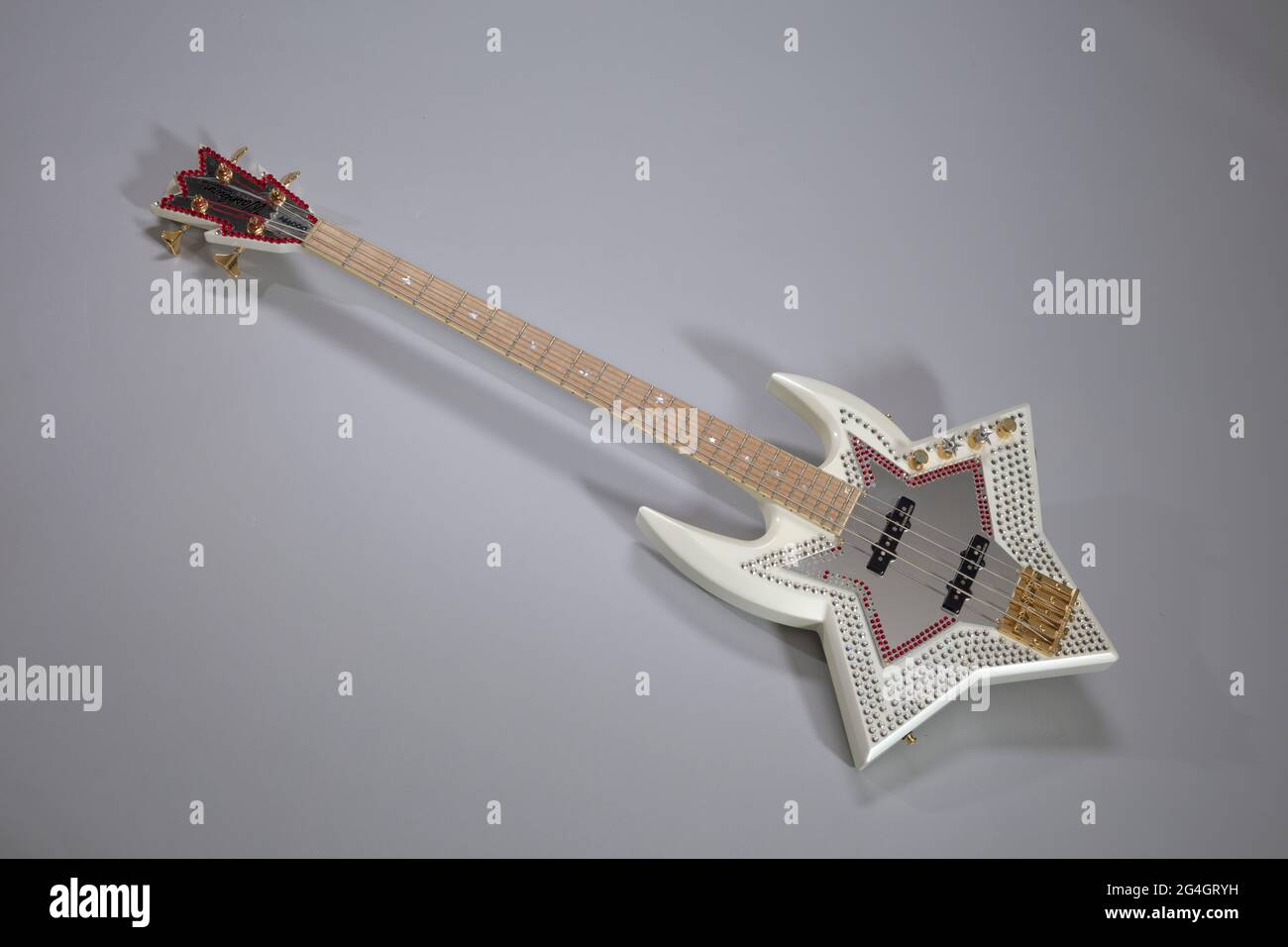 A limited edition, Bootsy Collins Space Bass from Washburn Guitars (TR2013-140.1.1) owned by Bootsy Collins. This is a four-stringed electric bass guitar with an asymmetrical star shaped body modeled from Bootsy Collin's Space Bass guitar. The guitar is decorated with silver and red crystal elements and a mirrored pickguard. The silver crystal elements on the bass guitar are in a star pattern around the pickguard. The red crystal elements decorate the edge of the mirror pickguard. Red and silver crystal elements decorate the headstock. The guitar has two (2) black electric pick-ups at the cent Stock Photo