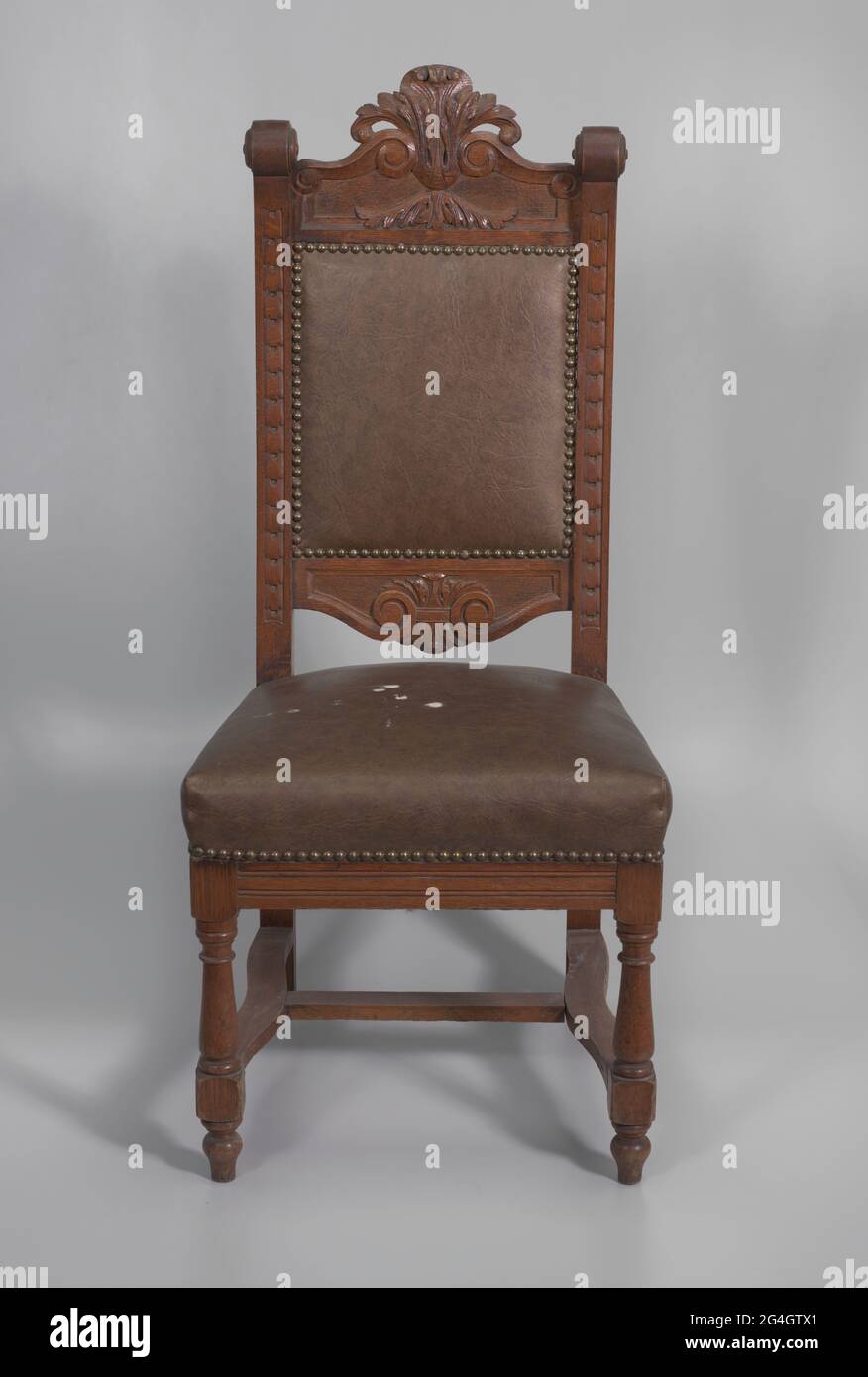 A wood pulpit chair with a dark finish. The chair has four legs with