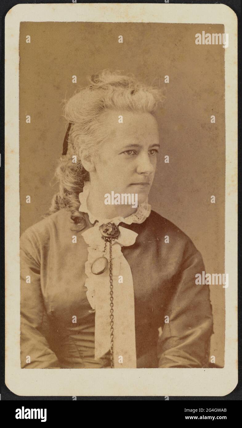 Carte-de-visite of Miss Thiele shown in half portrait. Her body is facing the camera, but her head is turned one quarter to her left and she looks off camera. Her hair is gathered at the back of her head and hanging down in large ringlets. She wears a dark colored bodice with a ruffled white lace collar and a white ruffled ribbon at her front neck. A chatelaine is pinned at her front neck with a watch visible and a longer chain hanging down with an object at the end that is out of frame.;The photograph is housed in the album 2017.30. The album page has a triple-lined, gold border framing the p Stock Photo