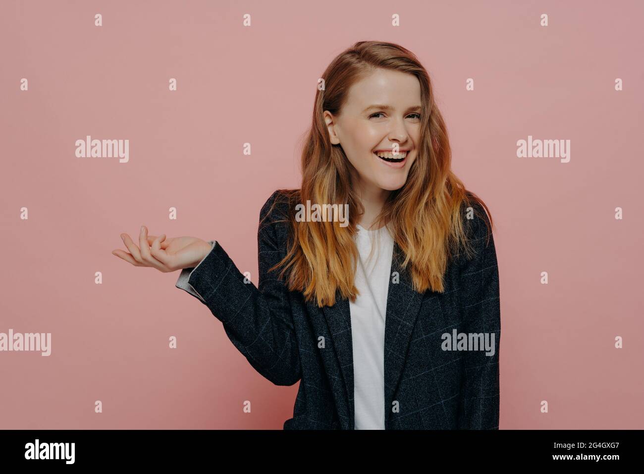 Laughing young woman with tipping hand shrugging shoulders Stock Photo