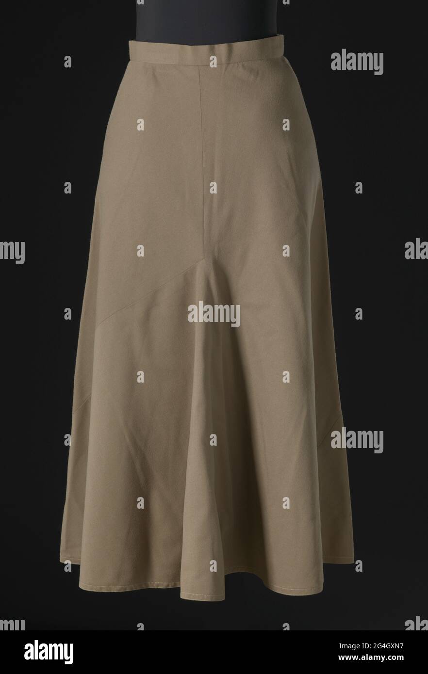 Taupe wool twill skirt designed by Arthur McGee. The skirt is made from two (2) pieces of fabric cut in the same asymmetric shape and then sewn together, with the pieces wrapping around the body and creating a full circle flair skirt. The skirt has a short waistband and falls just below the knee. It closes at the center back waist with a zipper and one (1) hook into a thread loop. The skirt is not lined and there are no labels. In 1957, Arthur Lee McGee (1933-2019) was the first African American designer hired to run a design studio on Seventh Avenue in the Garment District in New York City. Stock Photo