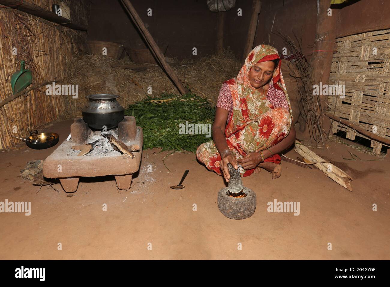 DHANKA TADVI TRIBE. Tadvi bhil woman using Pestle and Mortar for making chilly chuatney at Mogarapani Village in Akkalkuwa tehsil of Nandurbar Dist in Stock Photo