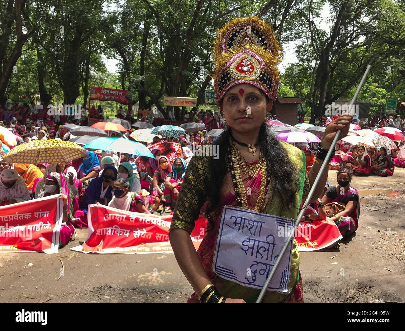 Kolhapur, Maharashtra, India. 21st June 2021. An ASHA worker is dressed as a goddess to kill the Coronavirus. More than 2000 ASHA workers protested at the district magistrate office in Kolhapur today for their three months pending salary and other demands. Accredited Health Care Workers (ASHA) are frontline workers in this pandemic. These brave people are overburdened with non-COVID and COVID tasks. They risk their life with inadequate safety gear and only 33 INR as their daily COVID incentive. The seventy thousand ASHA workers from Maharashtra are on indefinite strike for the last seven days Stock Photo