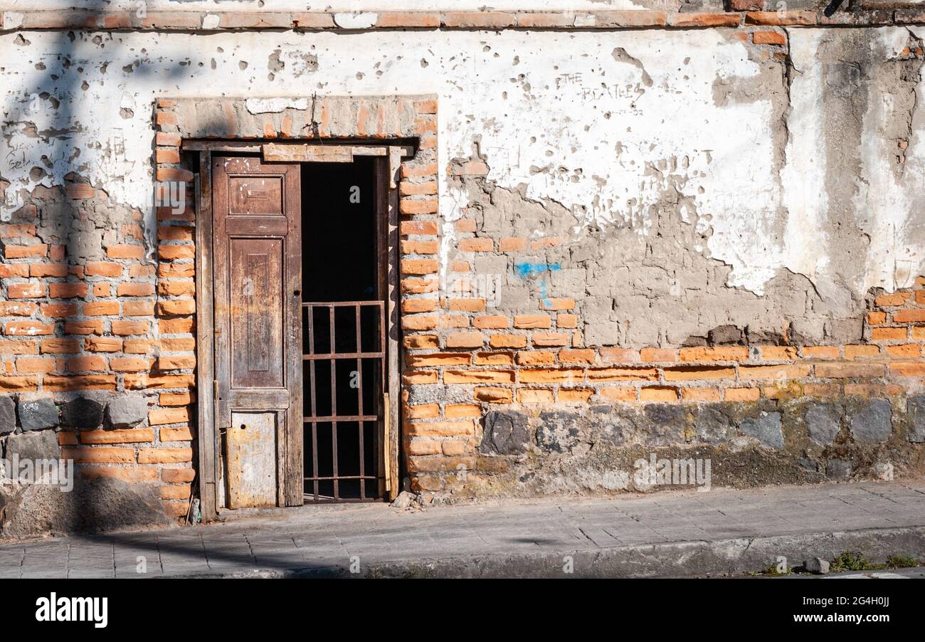 An iron gate partially blocks the half open door in an old red brick