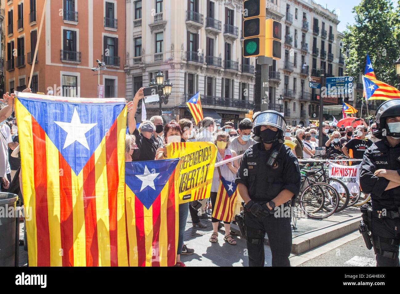 Protesters are seen with Catalan independence flags behind the police during the demonstration.Hundreds of Catalan independentistas have demonstrated in Las Ramblas in Barcelona, in front of the Gran Teatre del Liceu (Great Theater of the Lyceum), shielded by many policemen, to protest the visit of the President of the Spanish Government, Pedro Sanchez, who has held a conference entitled 'Reunion: a project for the future for all of Spain', with the expectation of an imminent granting of pardons for the independence leaders in prison. The protesters protested to denounce that the repression ag Stock Photo