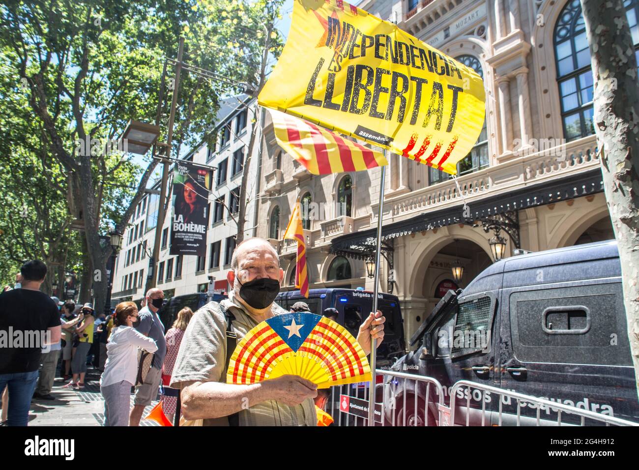A protester holding a Catalan independence flag and a symbol in front of the Gran Teatre del Liceu (Great Theater of the Lyceum) during the demonstration.Hundreds of Catalan independentistas have demonstrated in Las Ramblas in Barcelona, in front of the Gran Teatre del Liceu (Great Theater of the Lyceum), shielded by many policemen, to protest the visit of the President of the Spanish Government, Pedro Sanchez, who has held a conference entitled 'Reunion: a project for the future for all of Spain', with the expectation of an imminent granting of pardons for the independence leaders in prison. Stock Photo