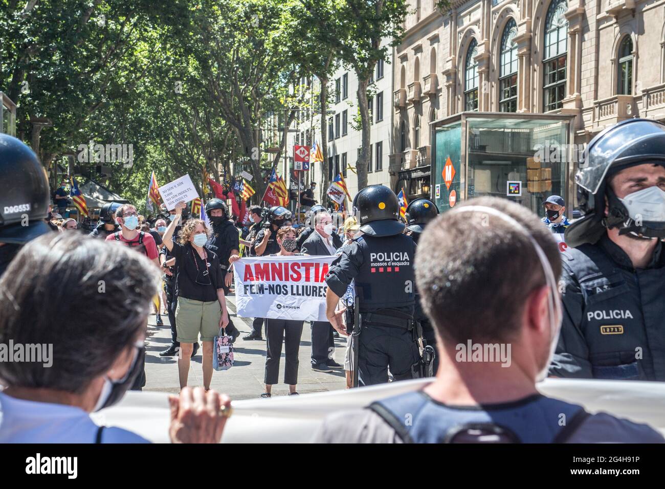 A protester confronts a policeman with a placard saying 'let's set free' during the demonstration.Hundreds of Catalan independentistas have demonstrated in Las Ramblas in Barcelona, in front of the Gran Teatre del Liceu (Great Theater of the Lyceum), shielded by many policemen, to protest the visit of the President of the Spanish Government, Pedro Sanchez, who has held a conference entitled 'Reunion: a project for the future for all of Spain', with the expectation of an imminent granting of pardons for the independence leaders in prison. The protesters protested to denounce that the repression Stock Photo