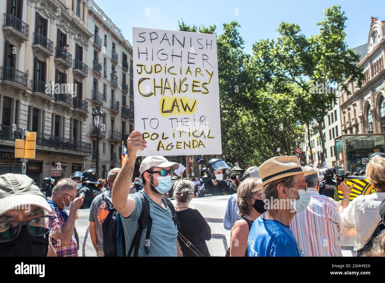 A protester holding a placard saying 'Spanish higher judiciary changes law to their political agenda' during the demonstration.Hundreds of Catalan independentistas have demonstrated in Las Ramblas in Barcelona, in front of the Gran Teatre del Liceu (Great Theater of the Lyceum), shielded by many policemen, to protest the visit of the President of the Spanish Government, Pedro Sanchez, who has held a conference entitled 'Reunion: a project for the future for all of Spain', with the expectation of an imminent granting of pardons for the independence leaders in prison. The protesters protested to Stock Photo