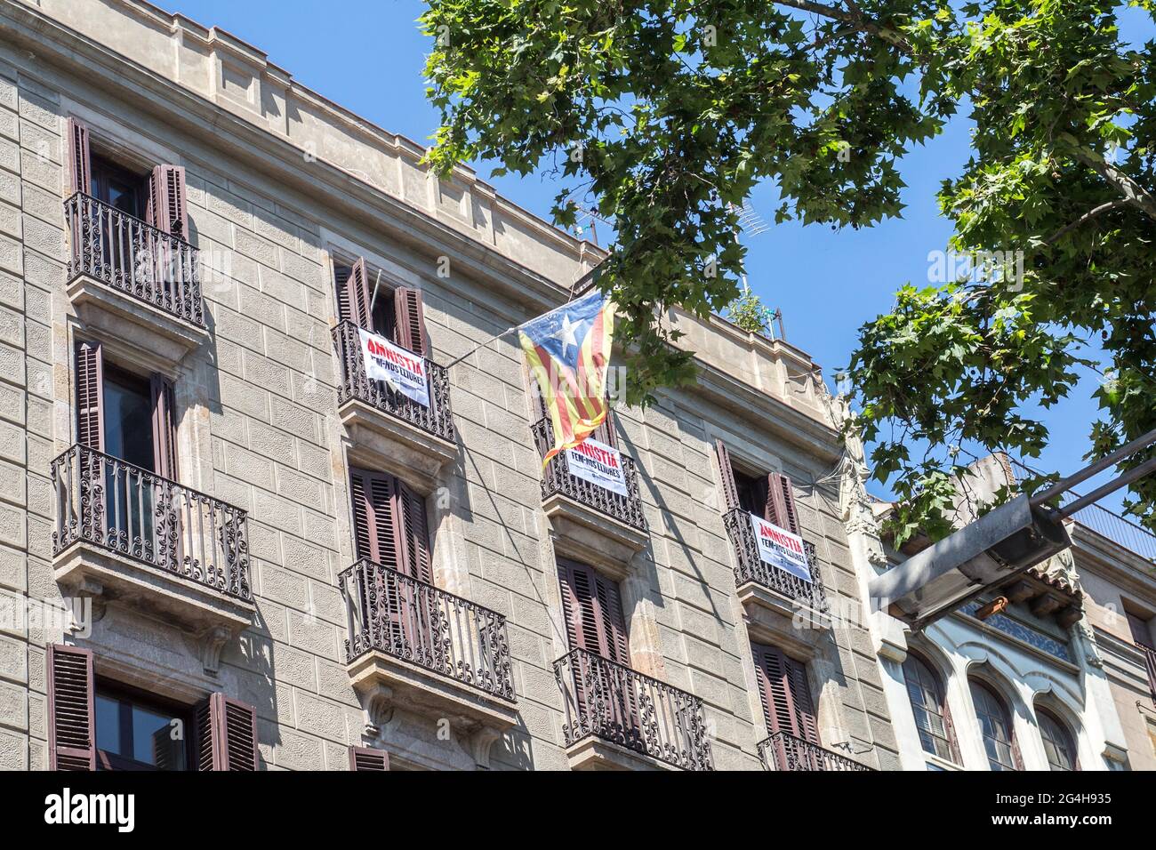 Catalan independence flag seen on a balcony with banners saying "let's set ourselves free" during the demonstration.Hundreds of Catalan independentistas have demonstrated in Las Ramblas in Barcelona, in front of the Gran Teatre del Liceu (Great Theater of the Lyceum), shielded by many policemen, to protest the visit of the President of the Spanish Government, Pedro Sanchez, who has held a conference entitled "Reunion: a project for the future for all of Spain", with the expectation of an imminent granting of pardons for the independence leaders in prison. The protesters protested to denounce t Stock Photo