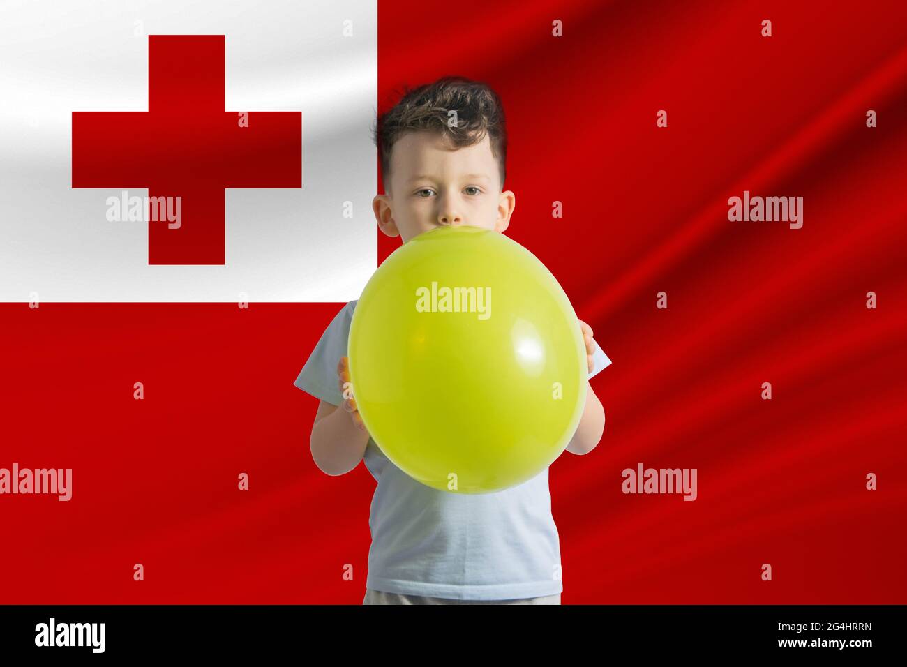 Children's day in Tonga. White boy with a balloon on the background of the flag of Tonga. Childrens day celebration concept. Stock Photo