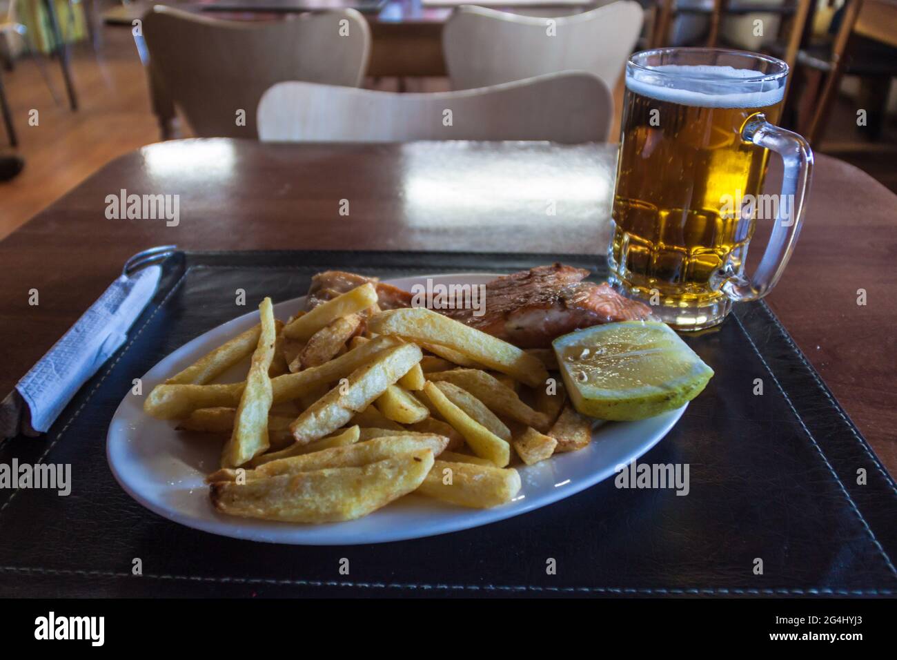 Salmon with fries, accompanied by a beer in restaurant in Castro, Chiloe island, Chile Stock Photo