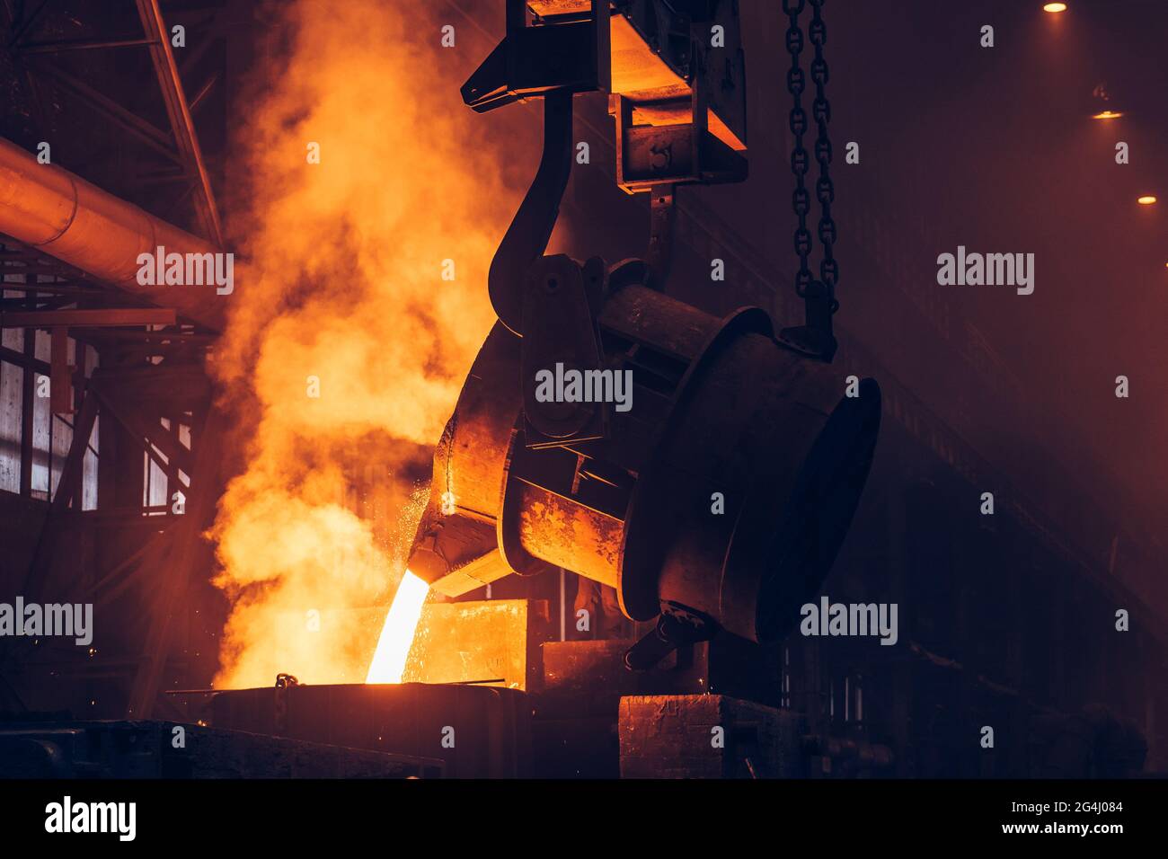 Molten metal casting. Pouring iron with smoke and sparks. Metallurgical plant. Steel production. Foundry blast furnace. Stock Photo
