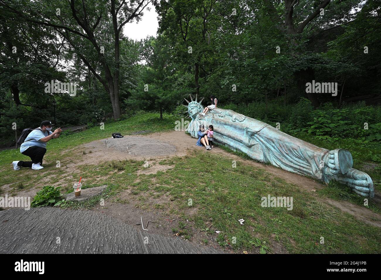 New York, USA. 21st June, 2021. A man takes a picture of his family in posing in front of “Reclining Liberty”, a 25 foot long replica of the Statue of Liberty sculptured by artist Zaq Landsberg, in Morningside Park, in New York, NY, June 21, 2021. (Photo by Anthony Behar/Sipa USA) Credit: Sipa USA/Alamy Live News Stock Photo