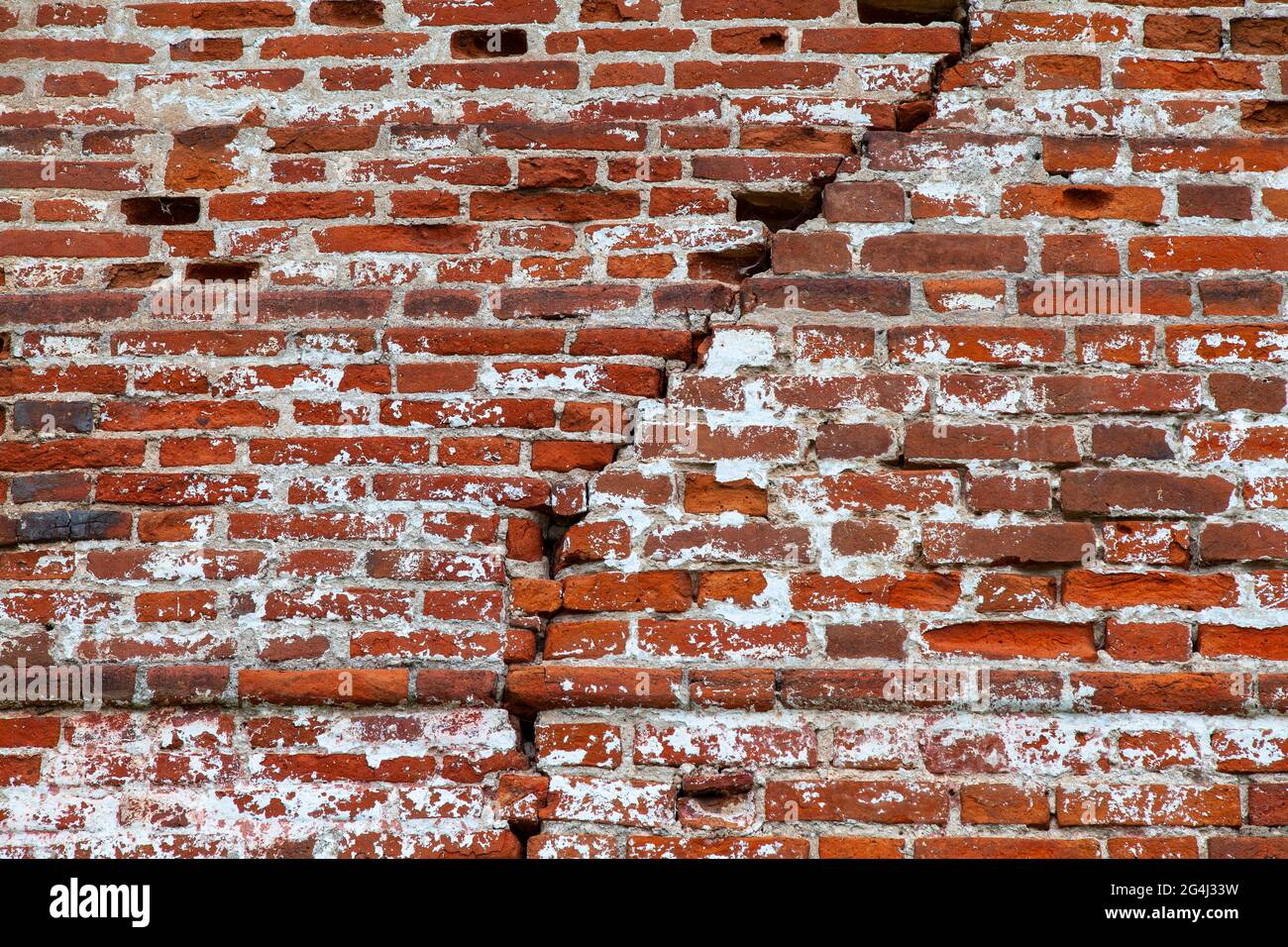Old red brick wall with a large crack. Stock Photo