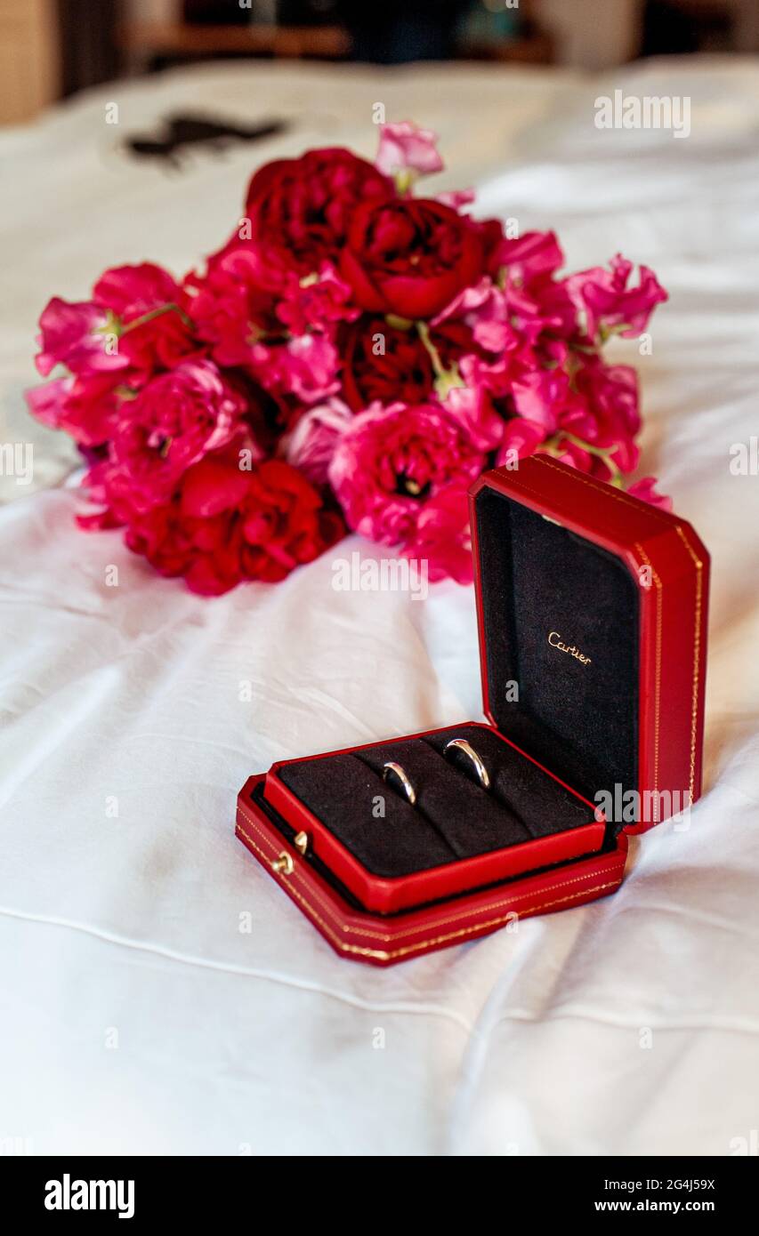 21 June 2021. Two gold wedding rings Cartier on the background of a wedding bouquet, in a red box. Holiday. Pink flowers. Editorial photo. Stock Photo