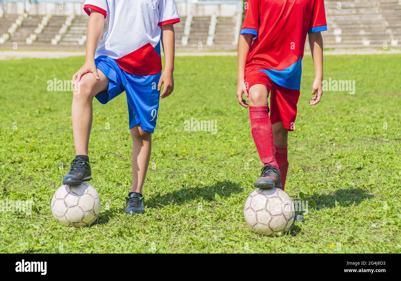 The cropped bodies of two young soccer players in white and red uniforms. Both are holding the