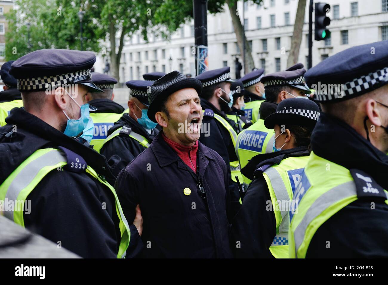 A anti-lockdown protester sings as he is being arrested by police close to Downing Street.  A demonstration was called as lockdown phase 4 is delayed Stock Photo