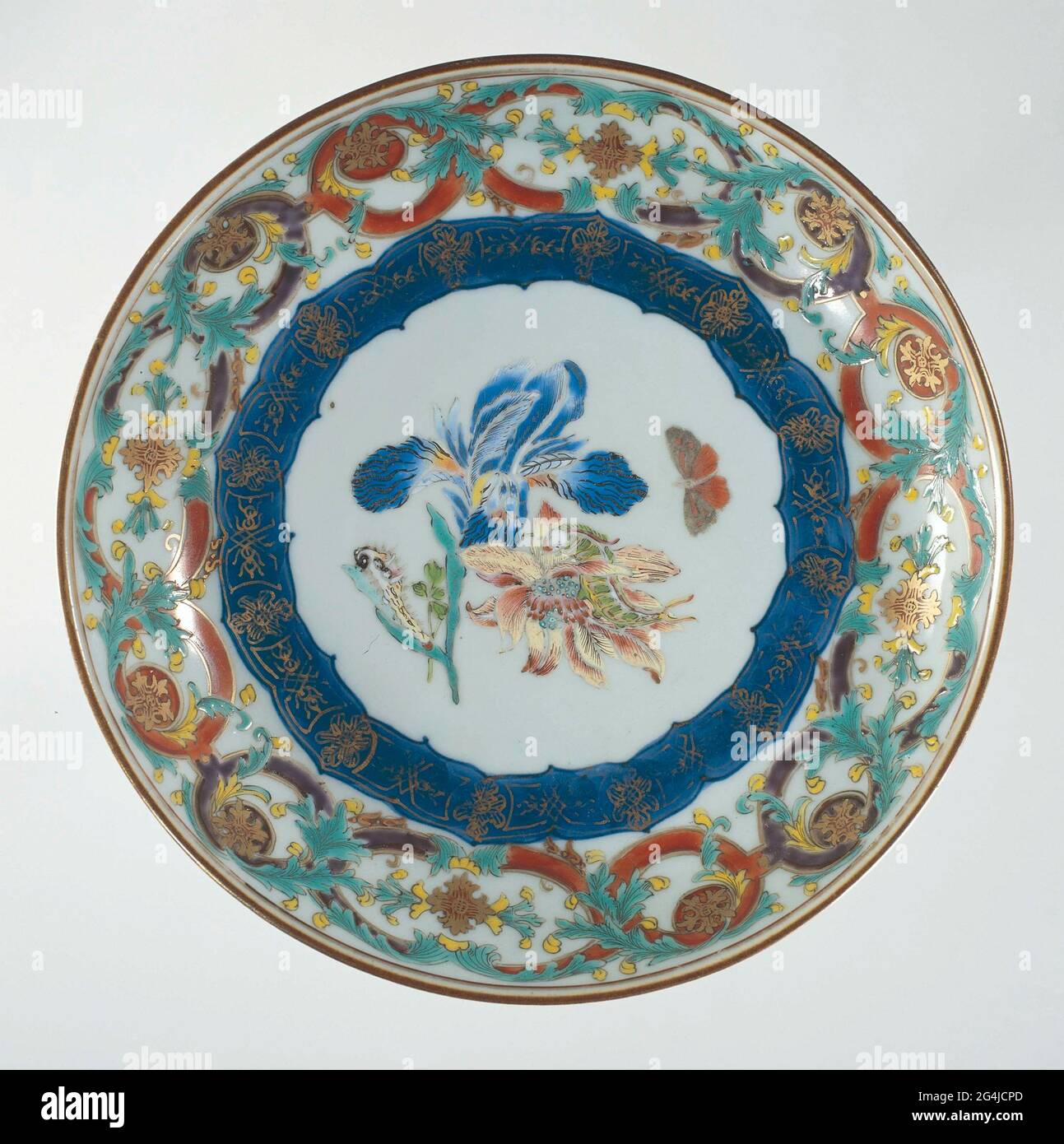 . Scale of porcelain with round wall, painted in underglaze blue and on the glaze in blue, red, pink, green, yellow, black and gold. On the flat two flower branches (iris, anemone) on which two caterpillars, next to it a flying butterfly; Here a decorative band in underglaze blue with gold; the wall a tire with a switched pattern with leaf raft; The outer edge with a tire napkin. European performance in email colors. Stock Photo