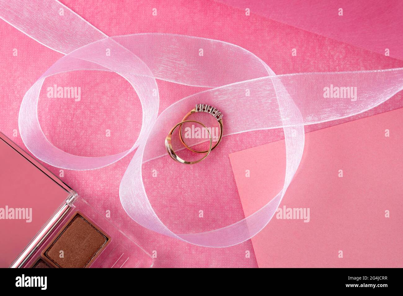 Gold rings lying on a pink table surface. Stock Photo