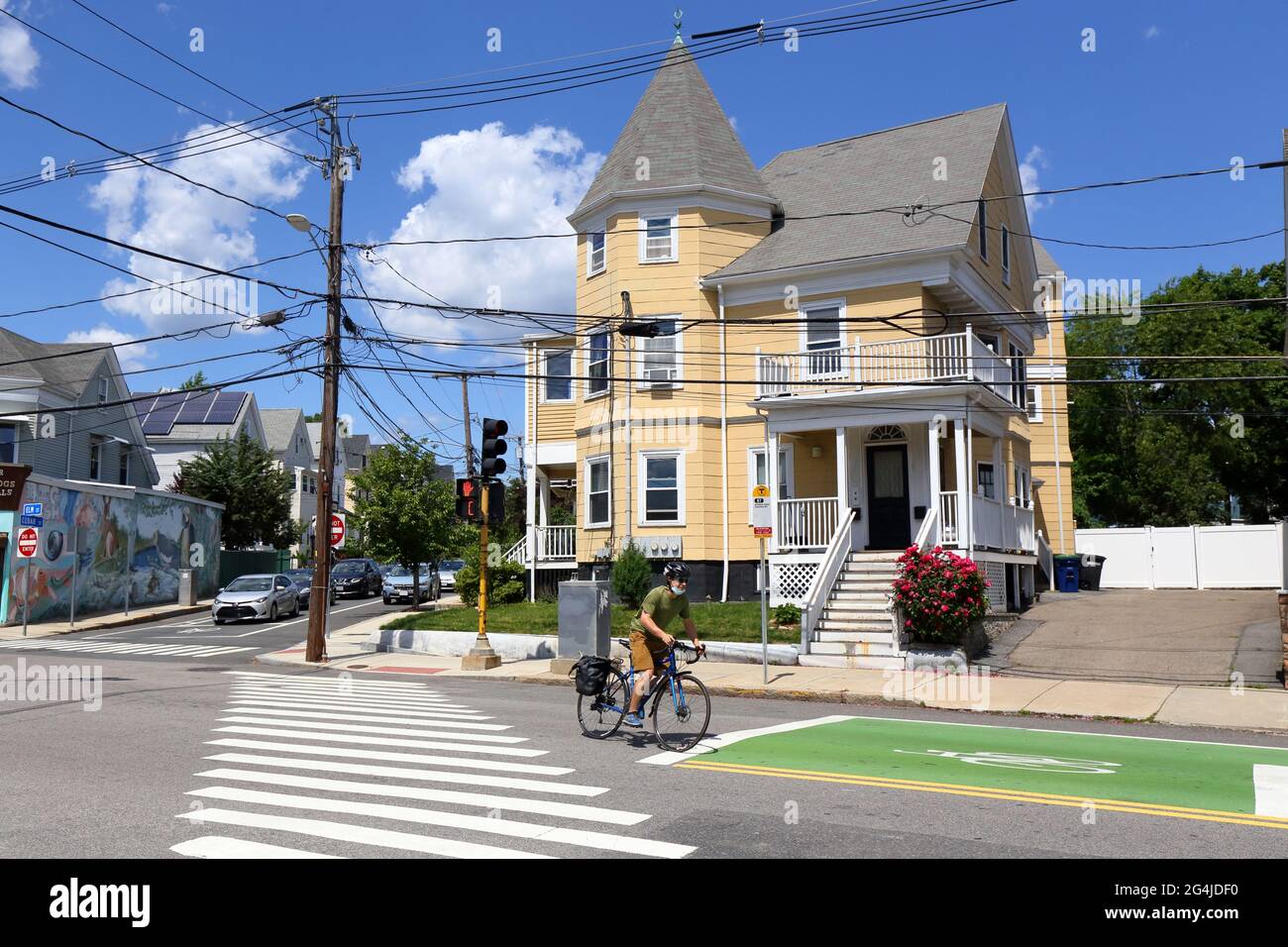A bicyclist rides downhill past a large house in the Spring Hill neighborhood of Somerville, Massachusetts, near Porter Square. Stock Photo
