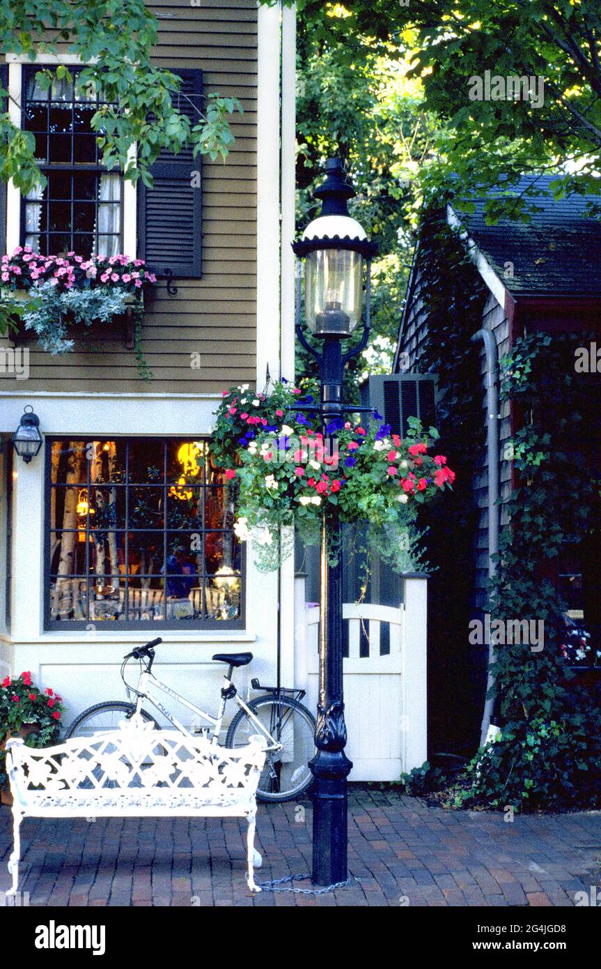 Shop with Bicycle, Lampost with Flowers and White Bench on the island of Nantucket, Massachusetts Stock Photo