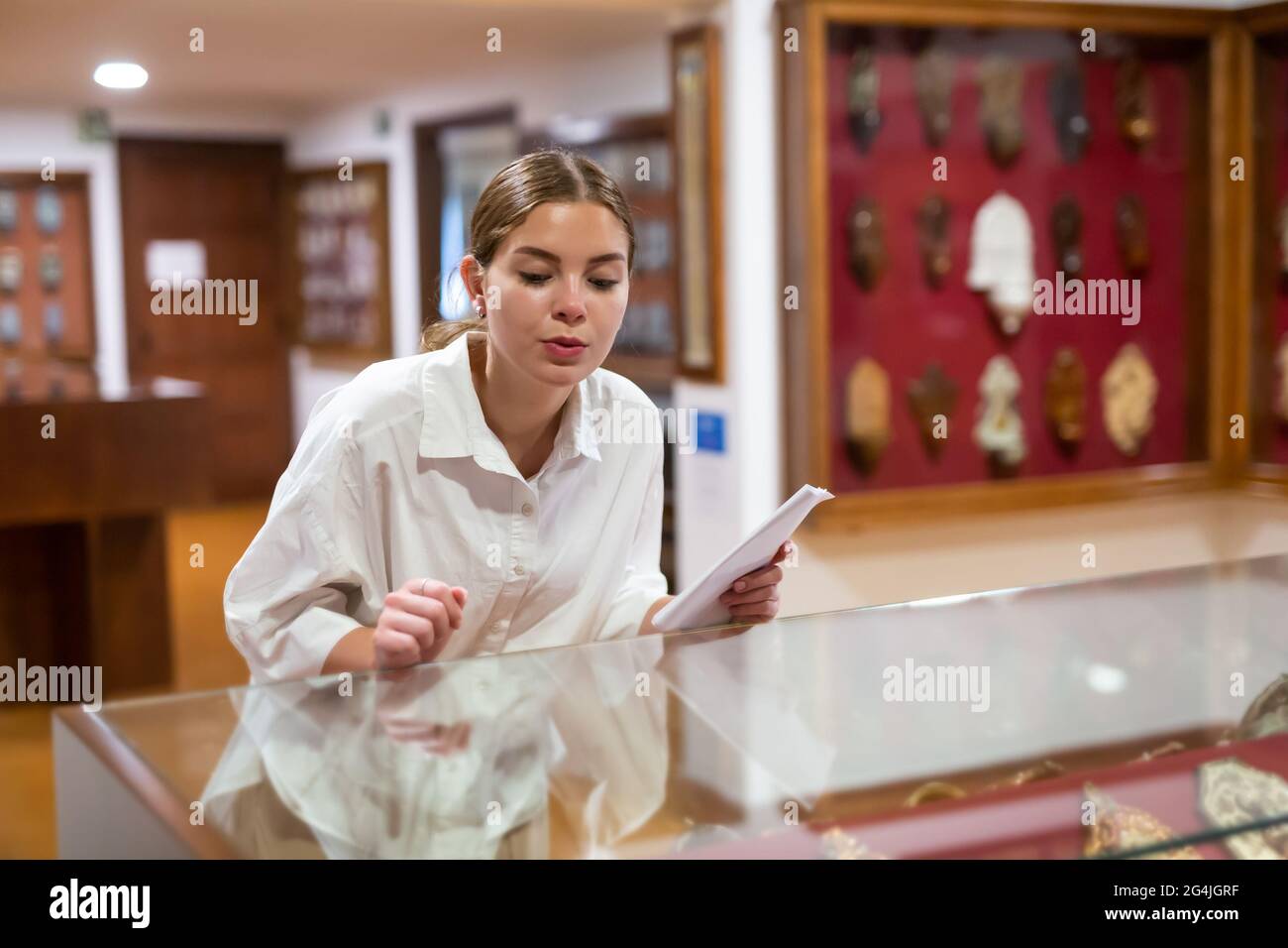 Woman looking at exhibits in glazed stands in museum Stock Photo