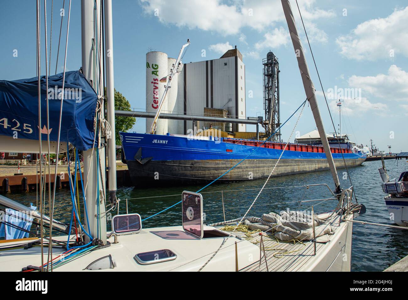 Fehmarn, Germany. 20th June, 2021. The multi-purpose vessel 'Jeanny' is moored in the municipal port of Burgstaaken in front of silos for feed and fertilizer. The harbour basin is to be dredged to a depth of five metres to make the small harbour competitive again. (to dpa 'Fehmarn wants to deepen Burgstaaken municipal harbour') Credit: Gregor Fischer/dpa/Alamy Live News Stock Photo