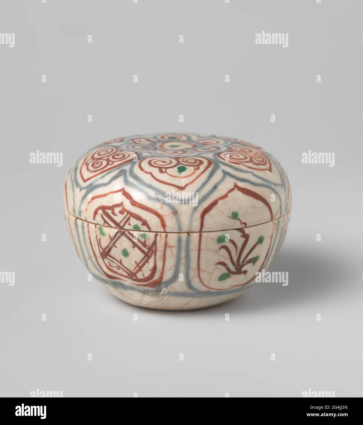 Box with Diaper Pattern and Flowering Plants in a Panel Decoration. Lid of box of stoneware, painted in underglaze blue and on the glaze red and green. On the wall of the box, continuous on the lid, scalloped cartouches with alternating napkin or a blooming plant. The top of the lid with a flower rosette surrounded by a band with a kind of ruyi motifs. Decoration Following the Chinese squirrch porcelain. Stock Photo