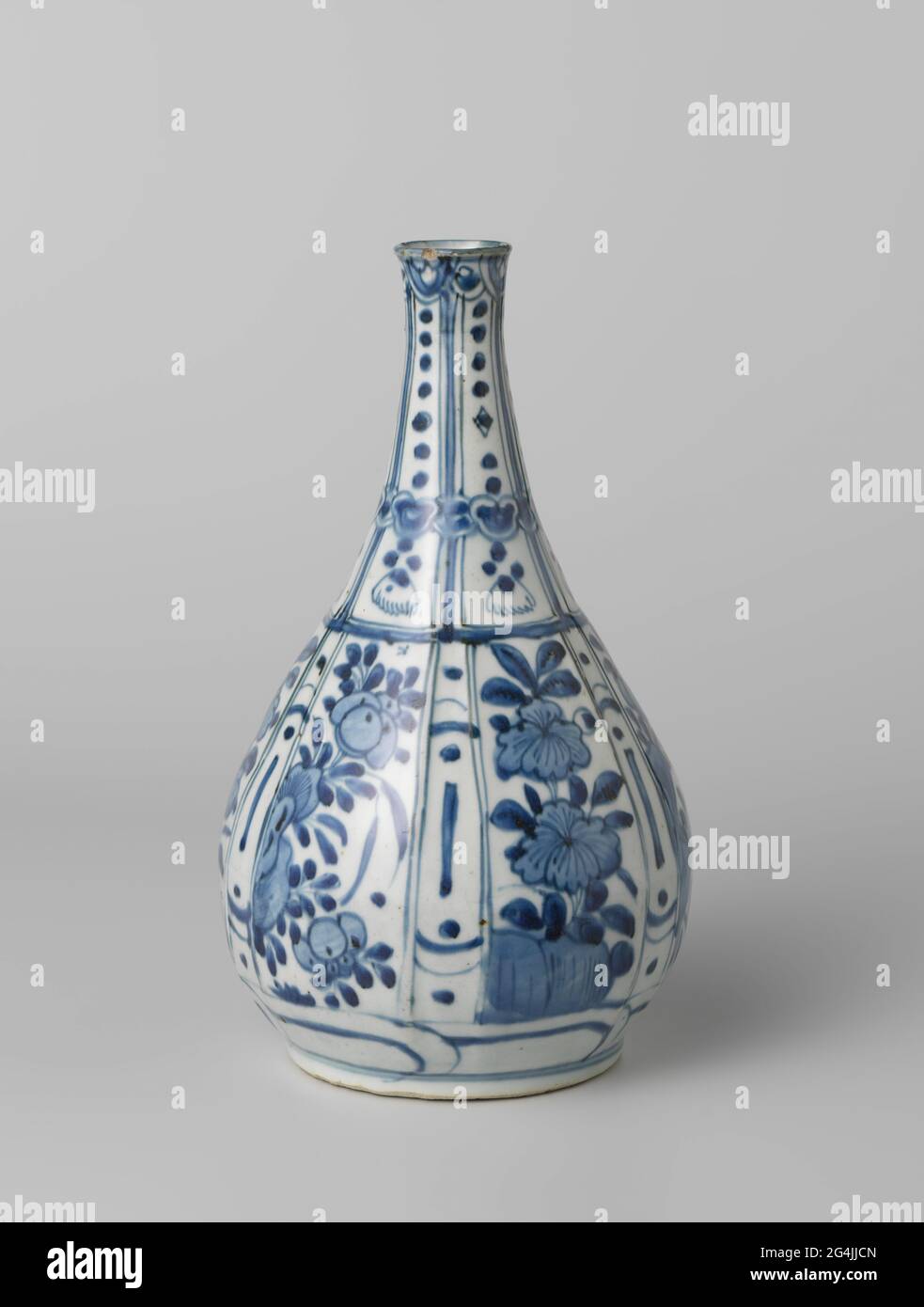 Pear-Shaped Bottle Vase With Flowering Plants And Dots in a Panel Decoration. Bottle-shaped vase of porcelain with a pear-shaped body and a slightly spreading neck, painted in underglaze blue. The outer wall is modeled on the belly in wide and narrow, rectangular compartments. In the wide boxes a thriving plant on a rock; The narrow compartments with stripes and dots. On the neck narrow, rectangular compartments with bead hangers with brushes. The courses are interrupted by a bond with Ruyi motifs. On the outer edge a band with flowers in medallions. A decorative band around the foot. A crack Stock Photo
