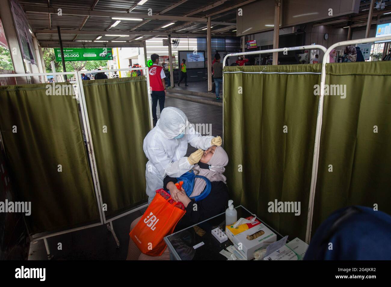 A health worker dressed in a protective suit conduct an antigen test on a passenger at the