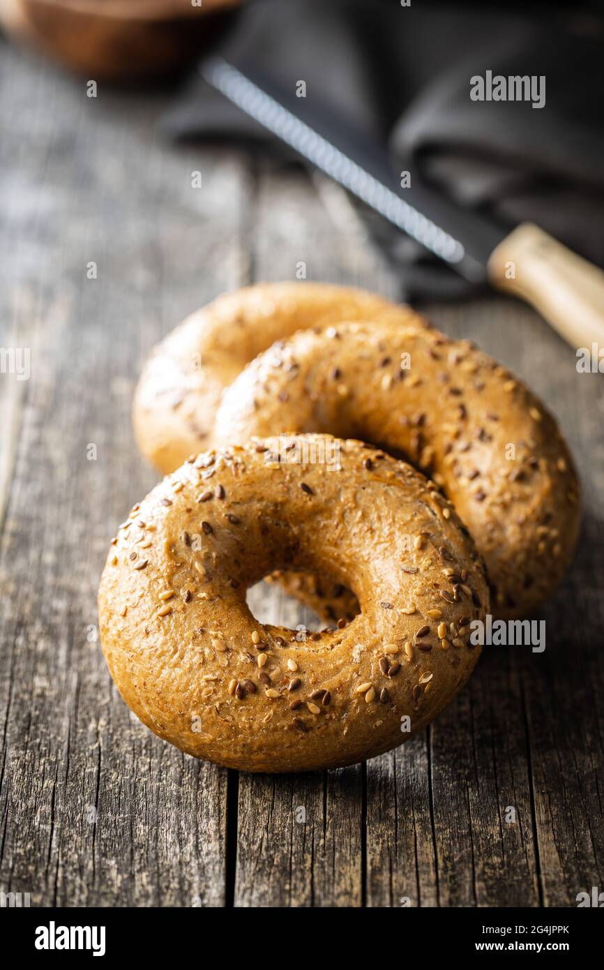 Whole grain baked bagel on wooden table. Stock Photo