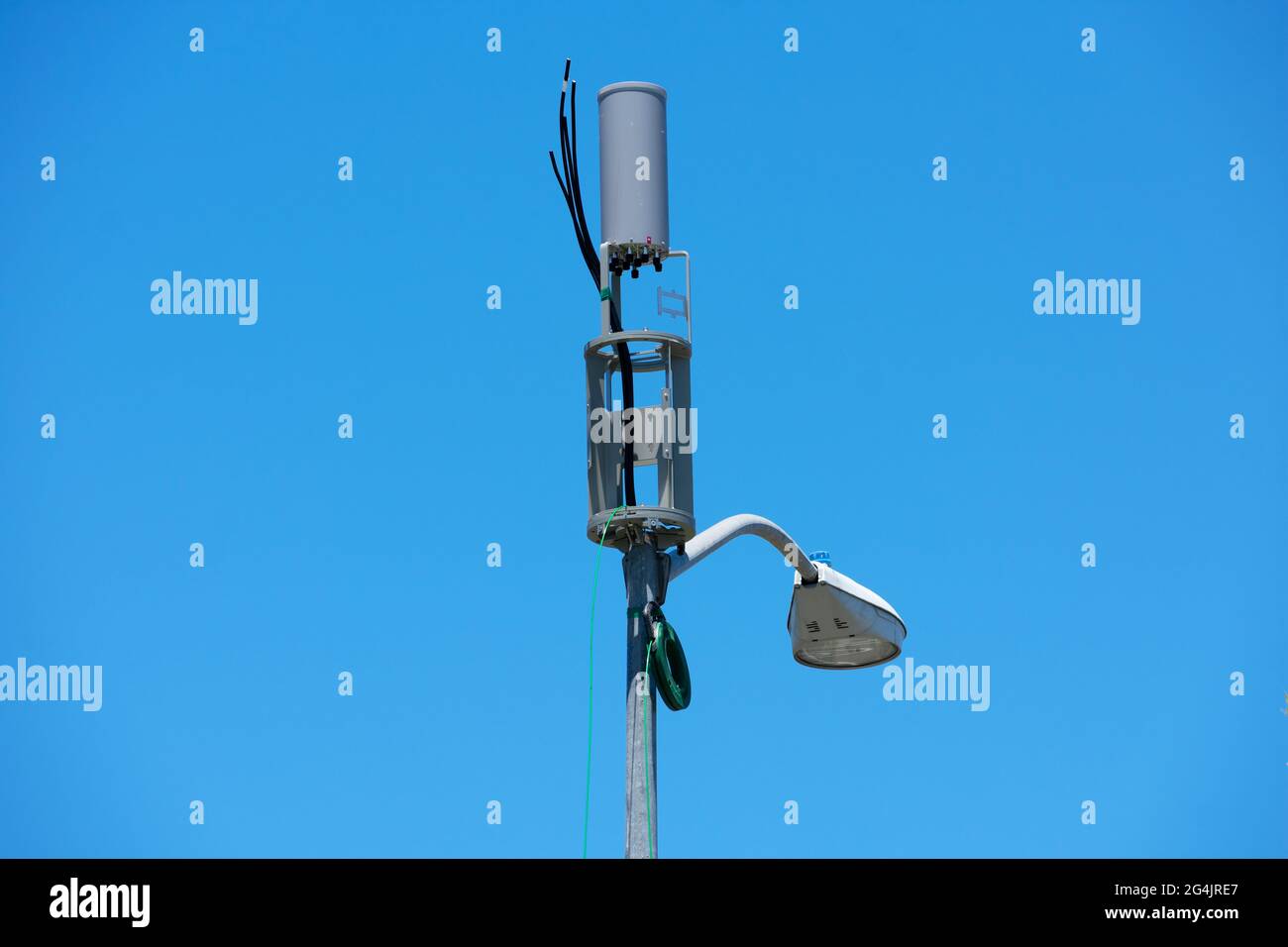 A small cell antenna installation on a lamp post is in progress. Protective antenna shroud removed, parts are visible and various cables are hanging i Stock Photo