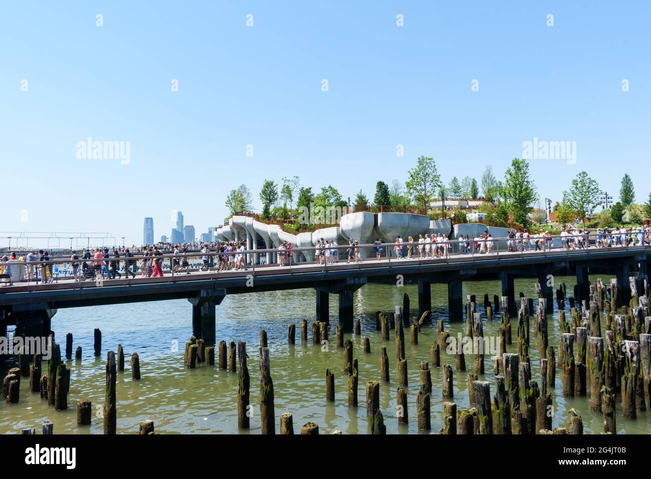 Crowds of tourists and visitors leaving and arriving to new, free public park Little Island at pier 55 on Hudson River. Remnants of an old pier in for Stock Photo