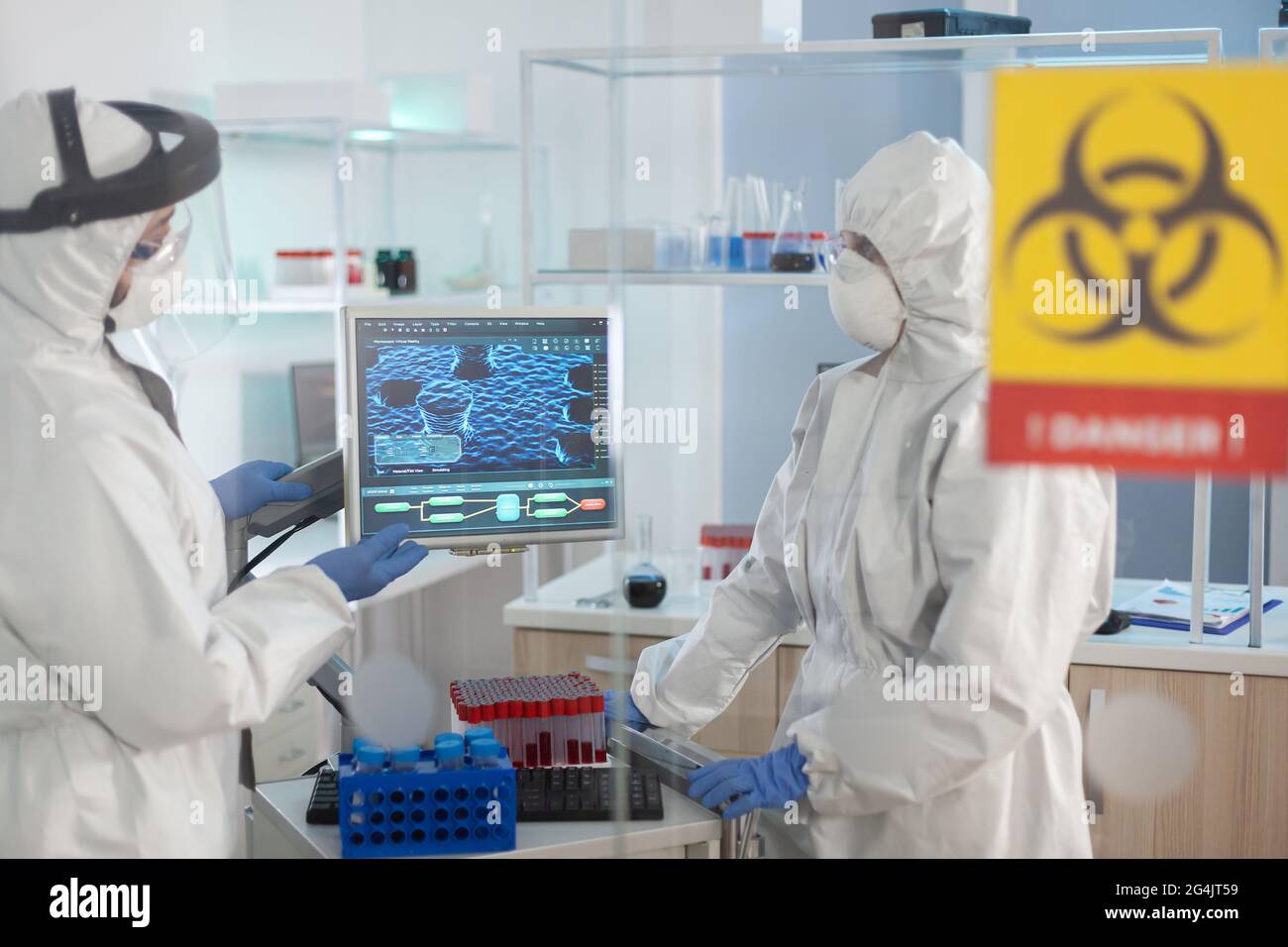 Scientists in ppe suit talking behind the glass wall working in ...
