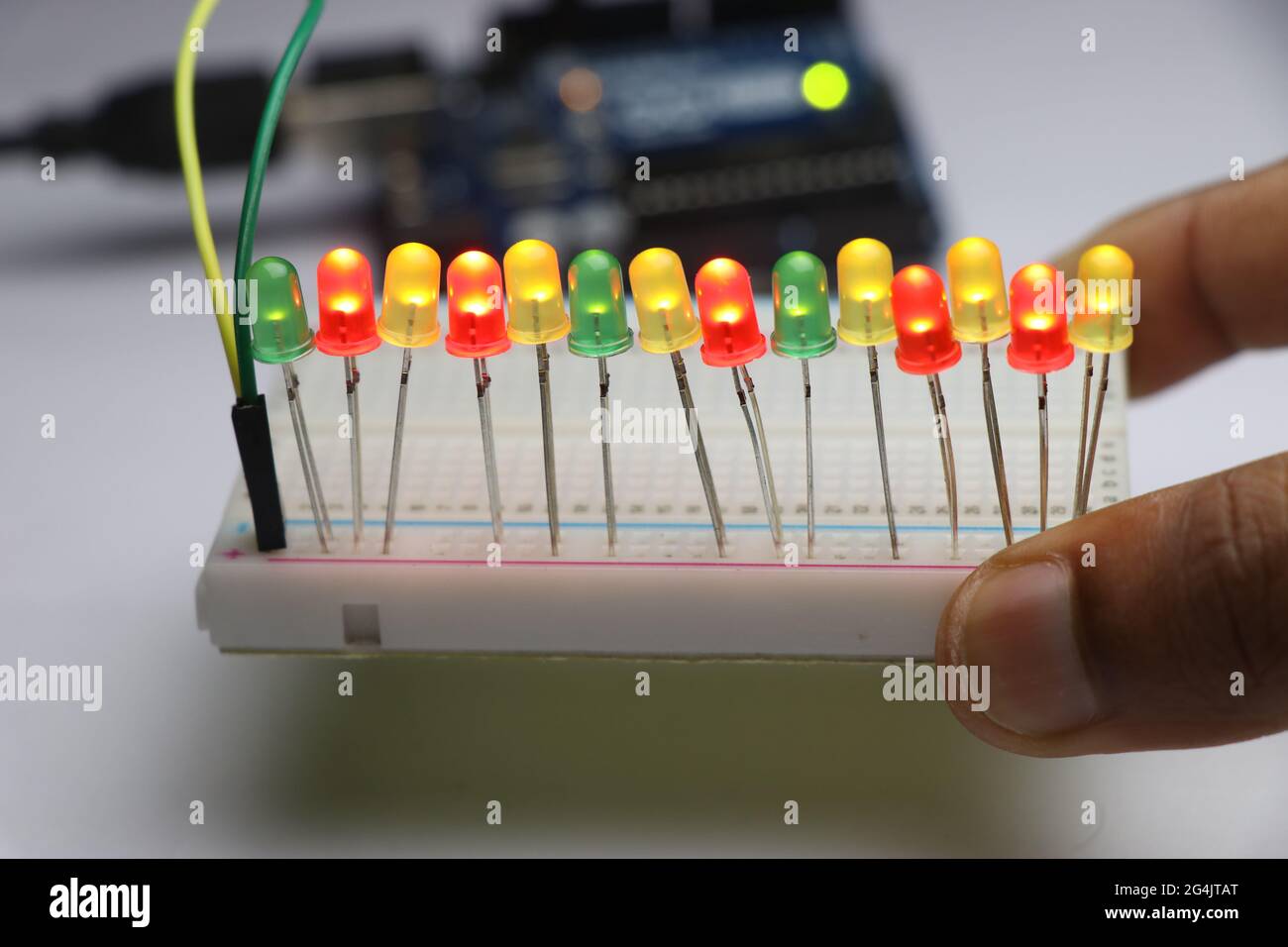 Light emitting diodes on breadboard with glowing lights controlled by micro  controller board on background held in hand Stock Photo - Alamy