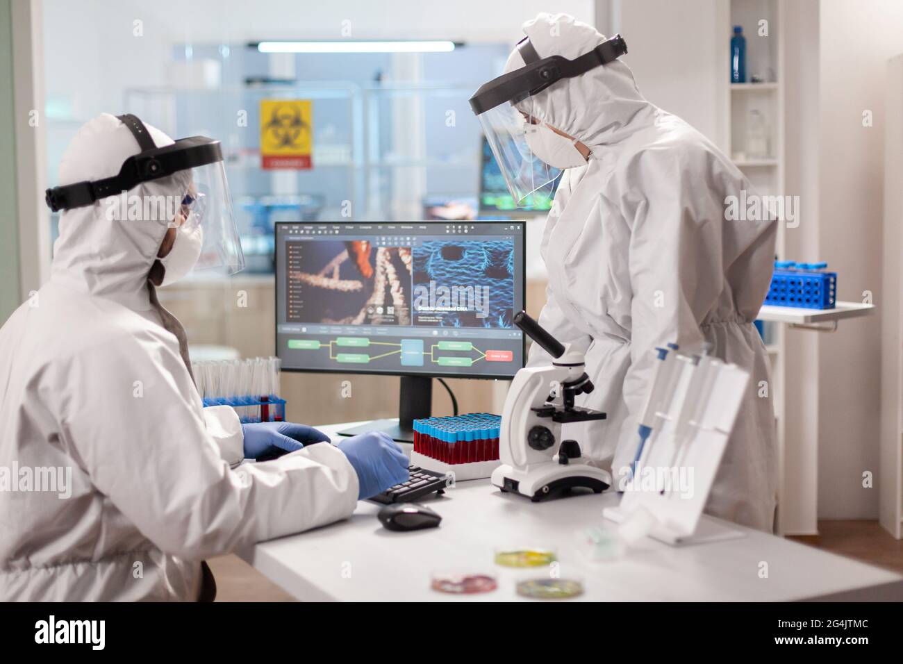 Scientists in protection suits analysing dna sample infected with virus. Team doctors working with various bacteria, tissue and blood samples, pharmaceutical research for antibiotics Stock Photo