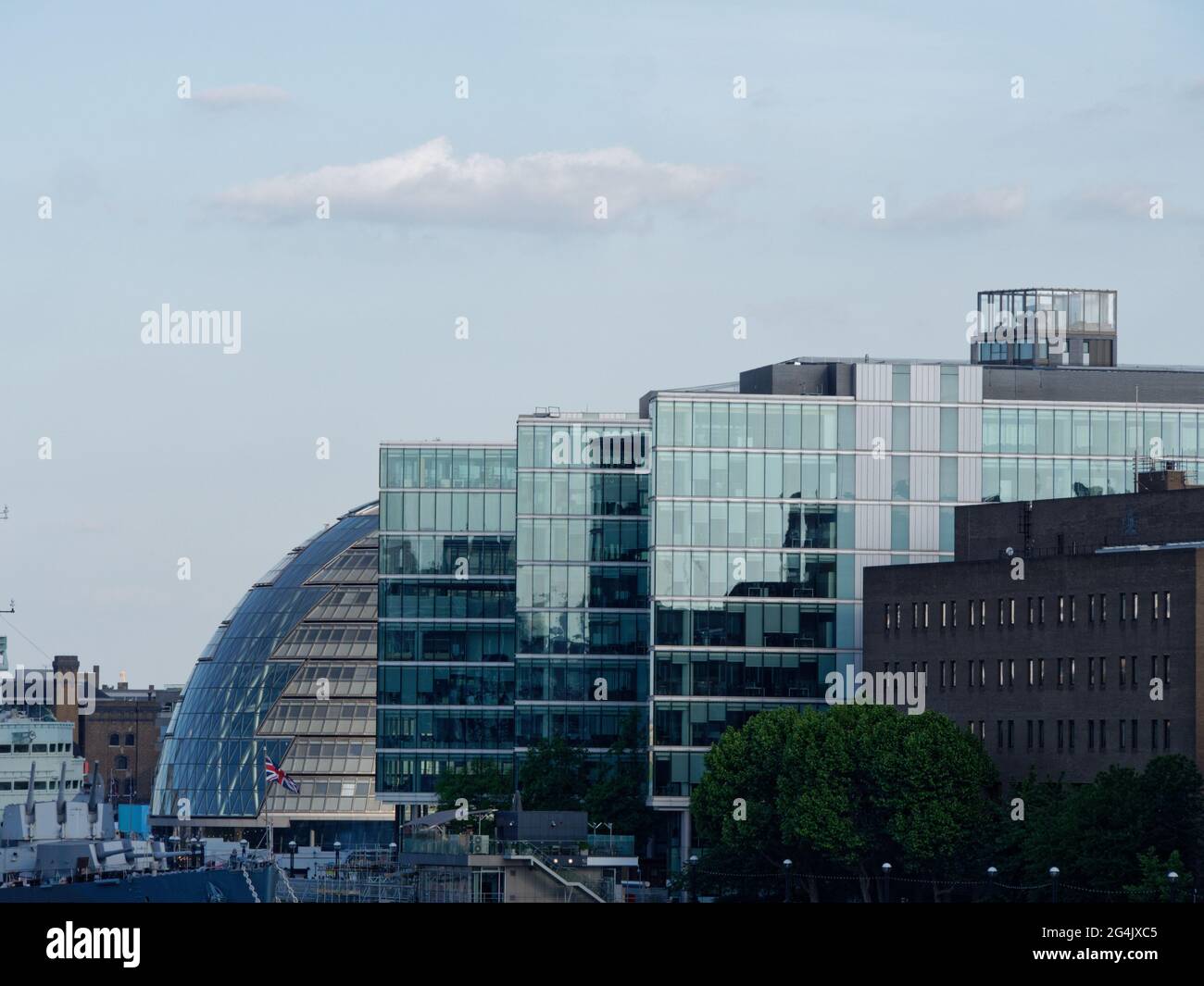 London, Greater London, England - June 12 2021: Modern building beside City Hall in Southwark with guns of ex warship HMS Belfast on the left. Stock Photo
