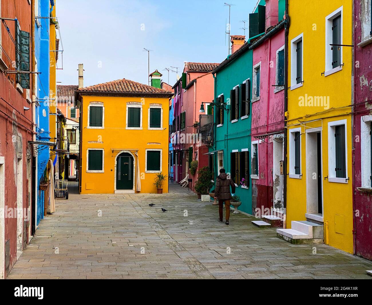 Unrecognizable person walking in the typical and very colorful streets of Burano. We see laundry being dried outside Stock Photo
