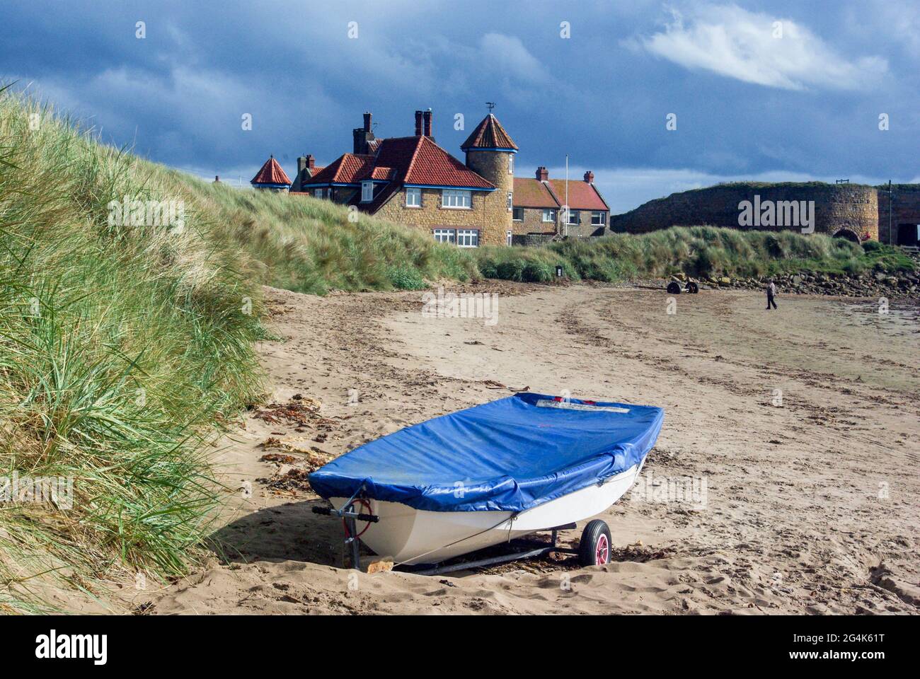 Beadnell Harbour, Beadnell, Northumberland, UK; boat with a blue cover on the beach. Stock Photo