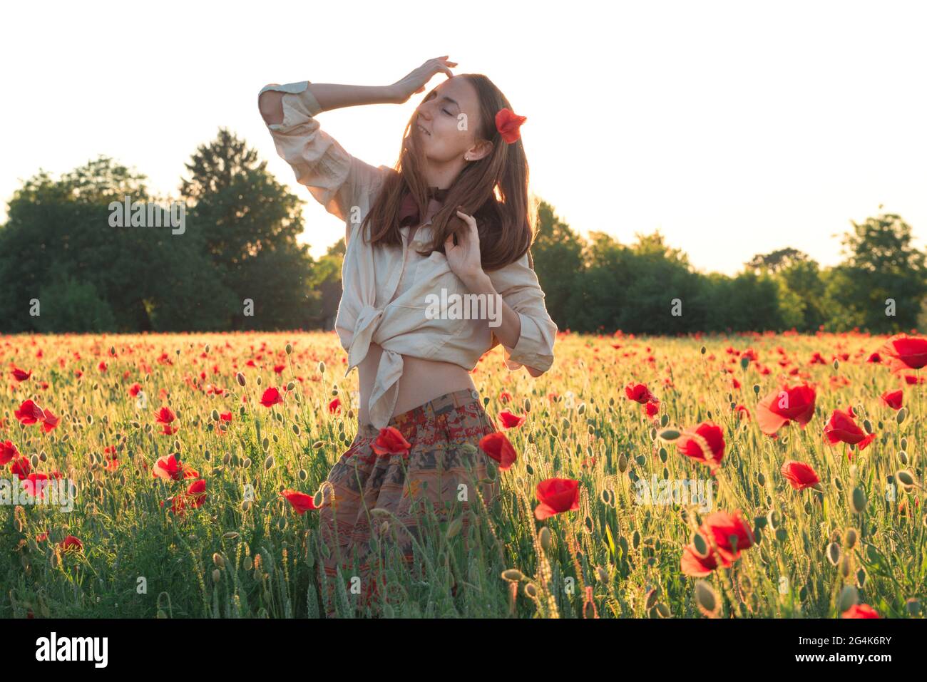 Young woman dancing on poppy field from back Stock Photo