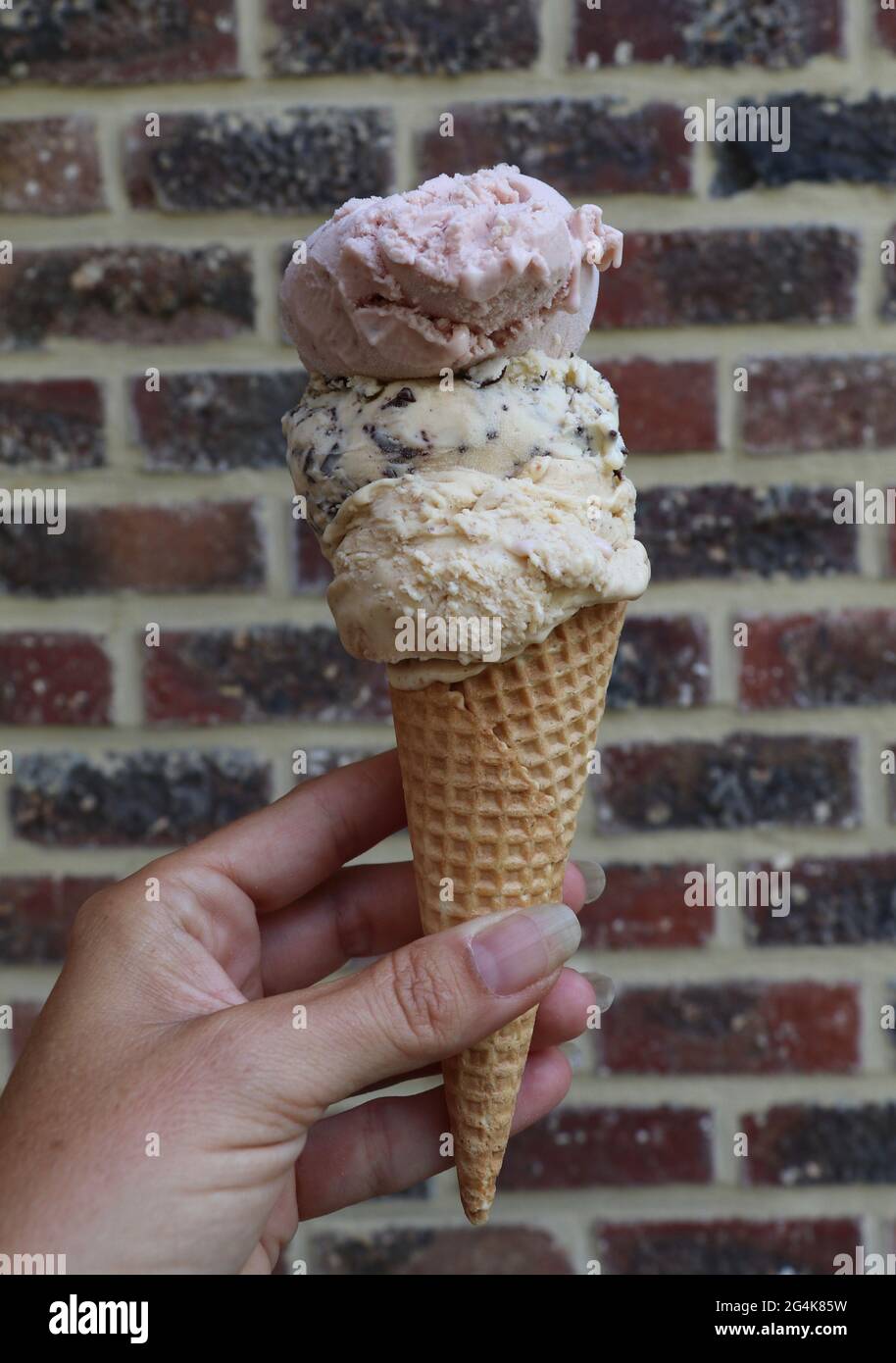 woman's hand holding a waffle cone with three scoops of ice cream Stock ...