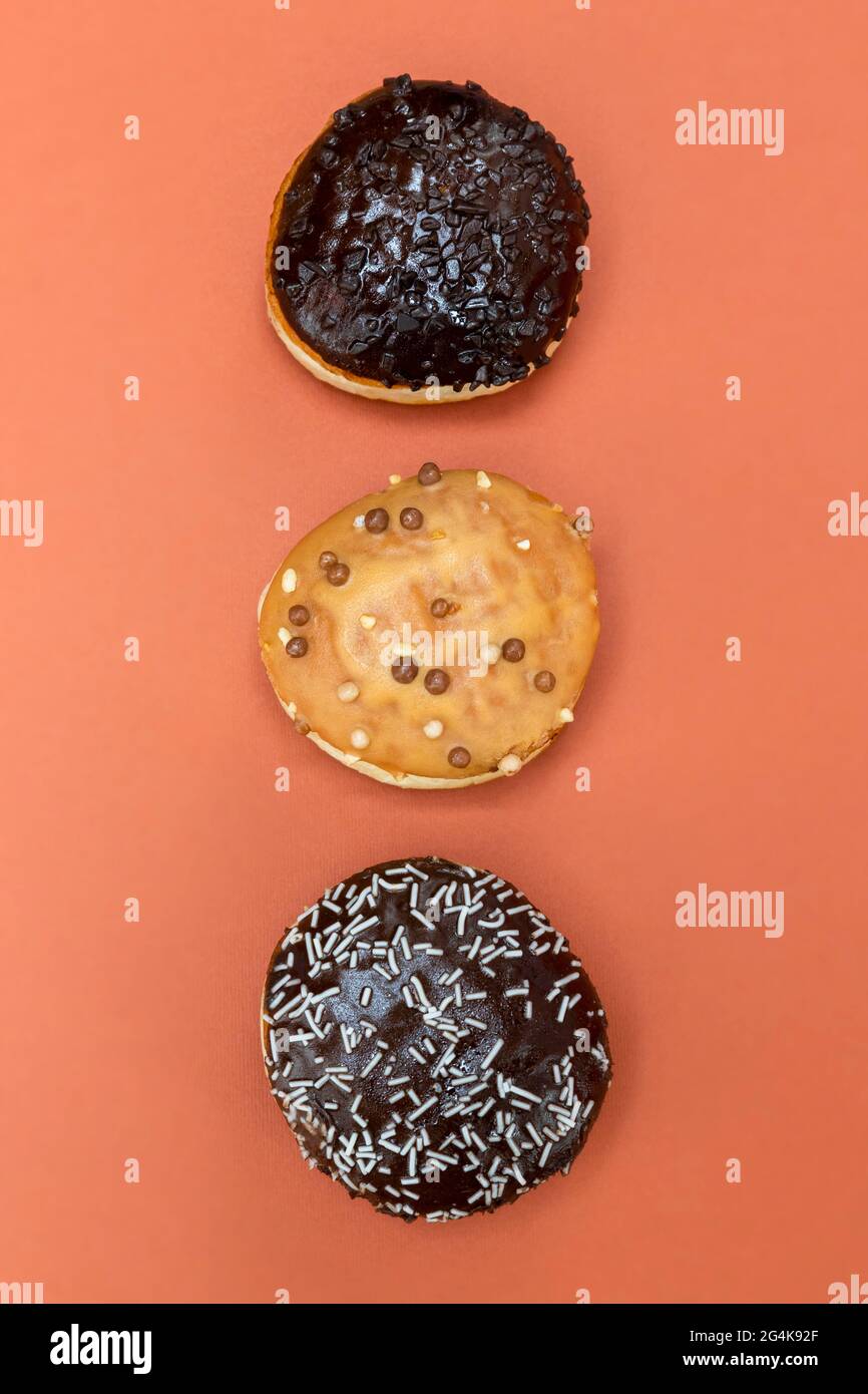 Delicious glazed chocolate donuts on vibrant background Stock Photo