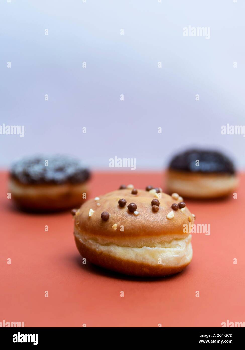Delicious glazed chocolate donuts on vibrant background Stock Photo