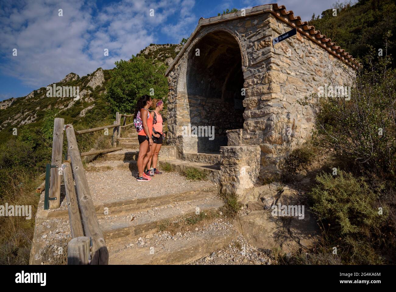 Hikers walking from Berga to the Queralt sanctuary along the Camí de la Solana path. Chapel of Sant Jacint (Berguedà, Catalonia, Spain, Pyrenees) Stock Photo